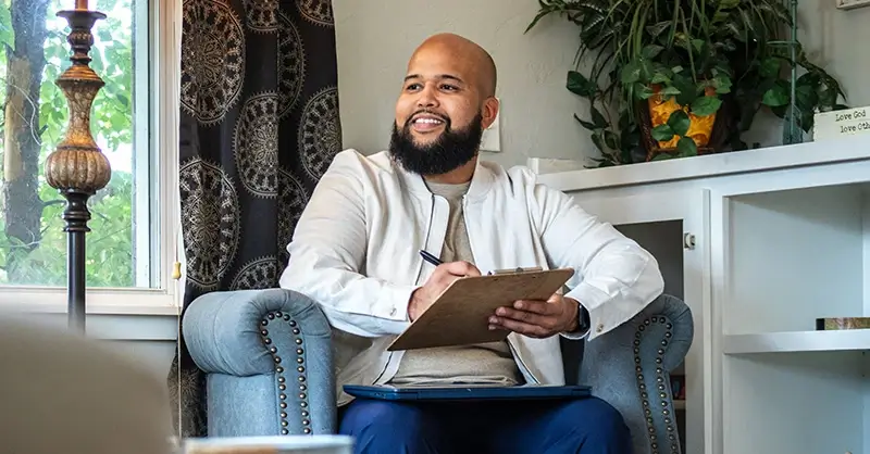 Terrance meeting with a client and writing on a clipboard 